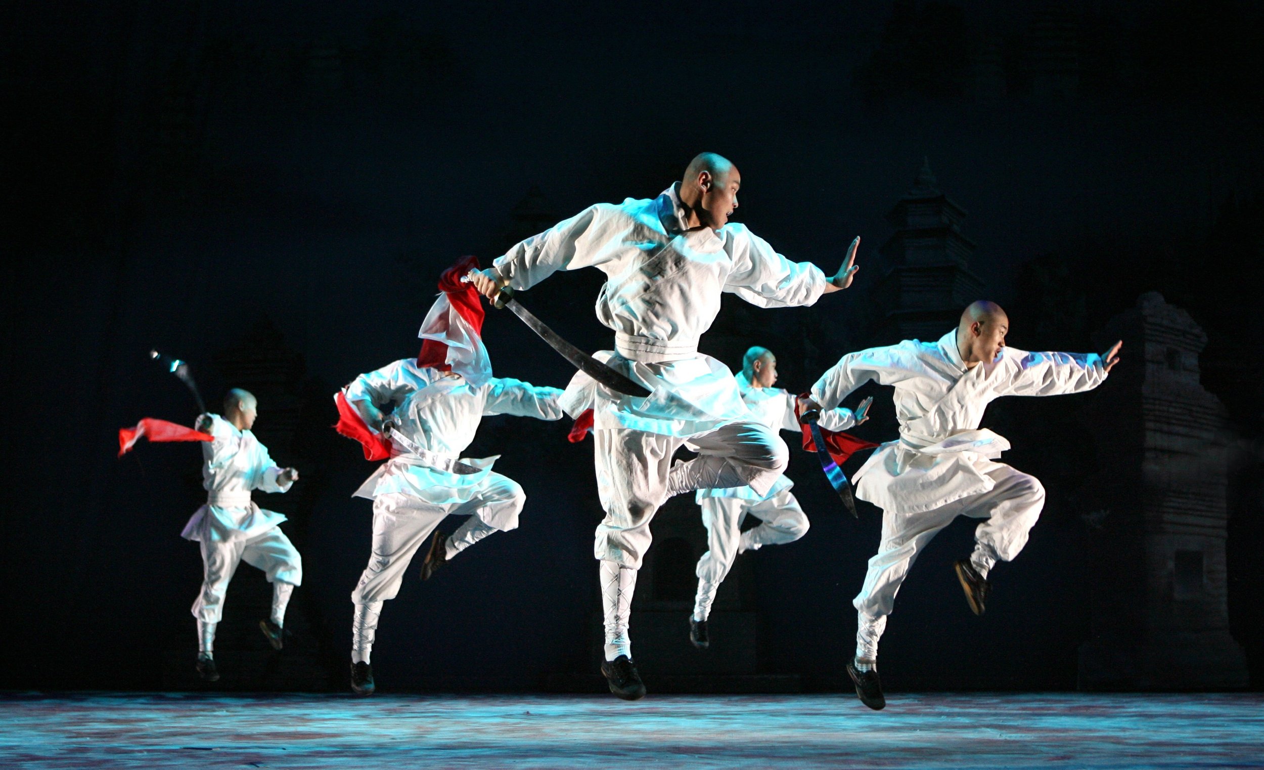 Martial artists leap in formation with swords